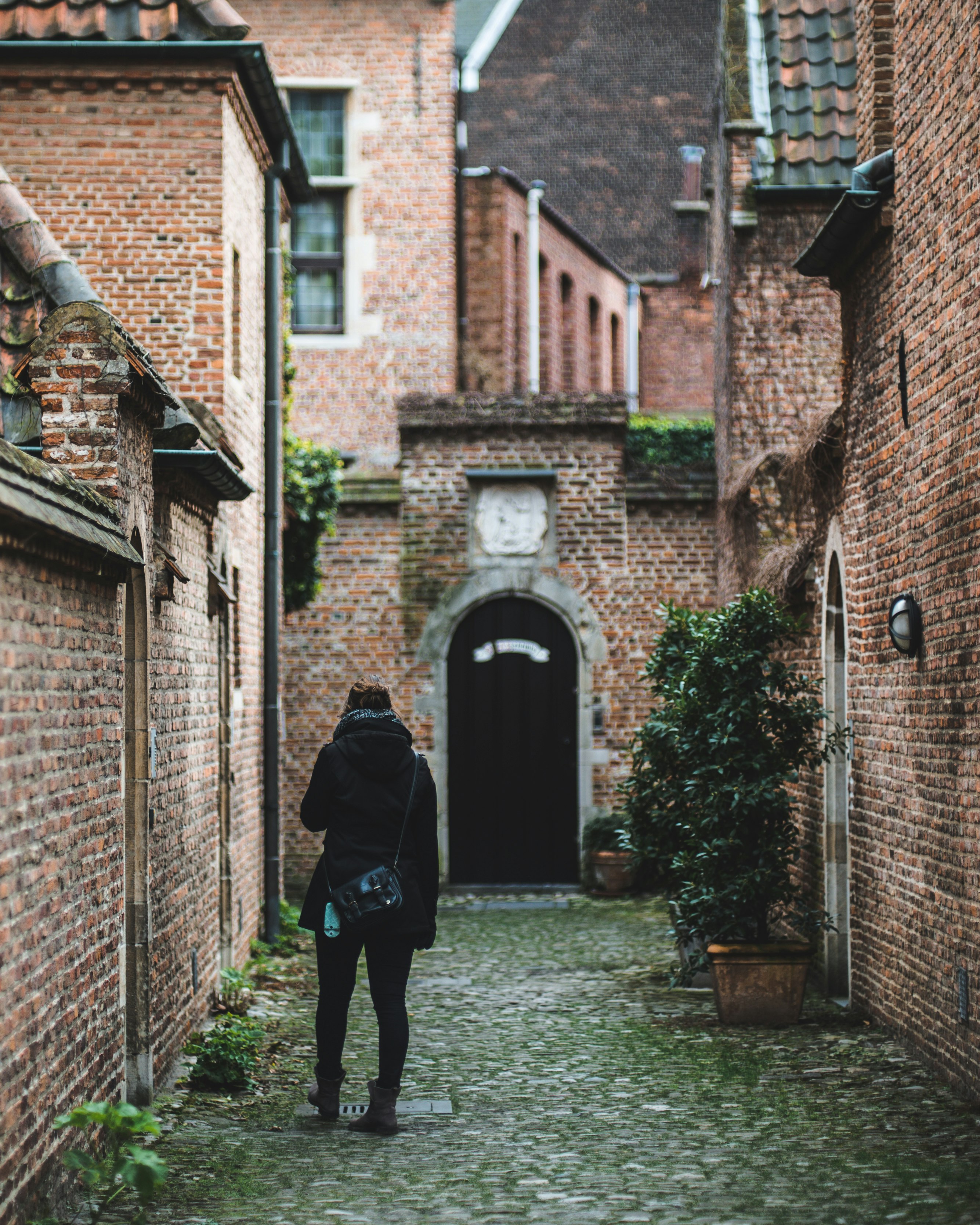 person in black jacket walking on sidewalk during daytime